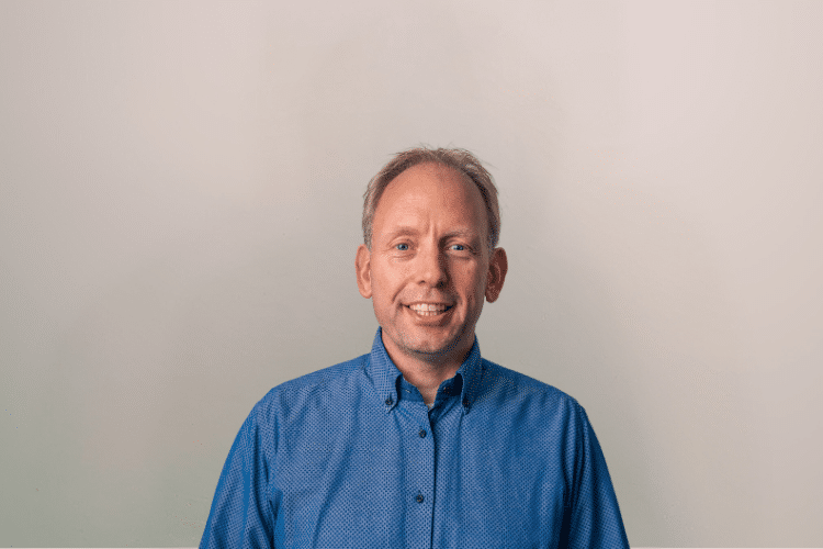 medewerker Qredits Peter Sanders man in blauw shirt voor grijze achtergrond