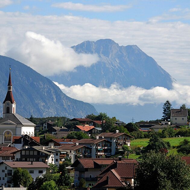 Een dorp in Oostenrijk tussen de bergen met een toren.