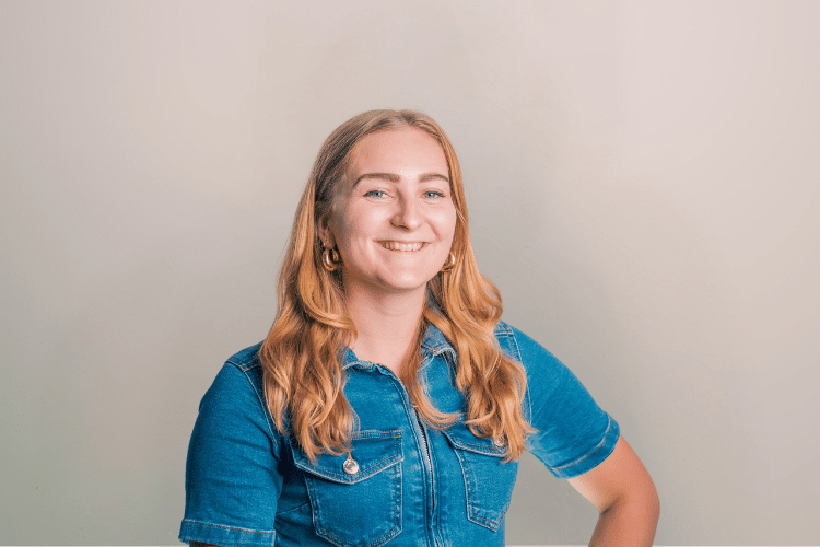 Teska medewerker Qredits vrouw in denim shirt voor grijze achtergrond