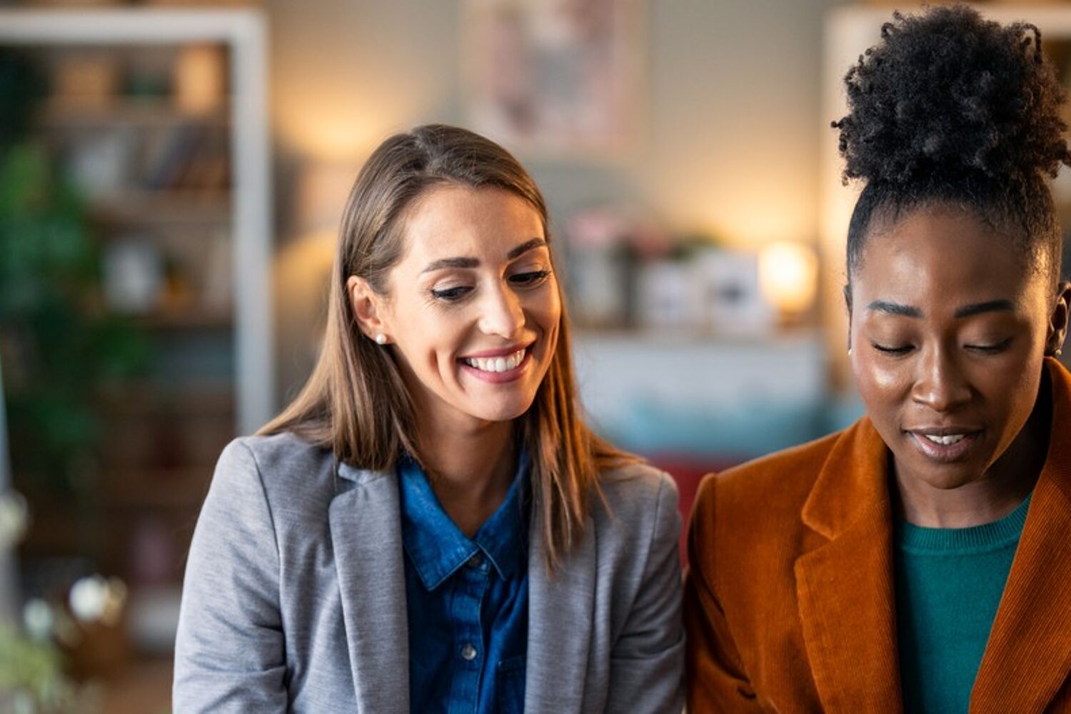 Twee vrouwen zitten aan tafel en kijken lachend naar ipad.