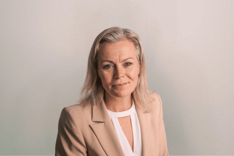 Kirsten medewerker Qredits vrouw in beige jasje voor grijze achtergrond