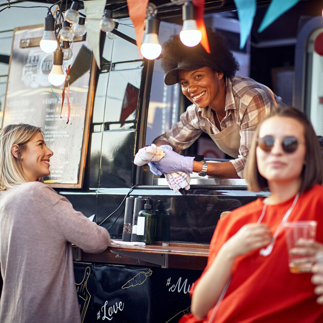 Vrouw staat in foodtruck en lacht.