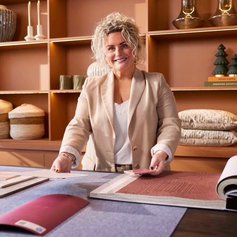 Lachende vrouw staat aan een tafel met een boek.