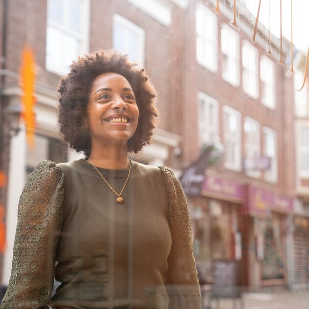 Lachende vrouw kijkt door een raam naar binnen heen. 