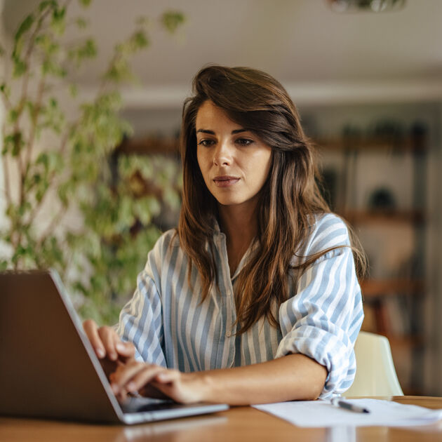 Vrouw kijkt serieus naar laptop.