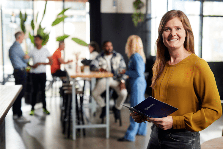 Vrouw in geel shirt met Qredits boekje bij een coach meeting