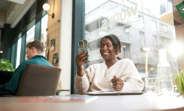 Vrouw kijkt lachend naar haar telefoon