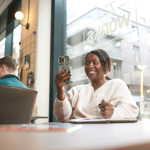 Vrouw kijkt lachend naar haar telefoon