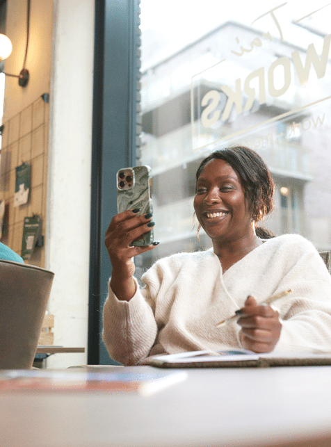 Vrouw kijkt lachend naar haar telefoon