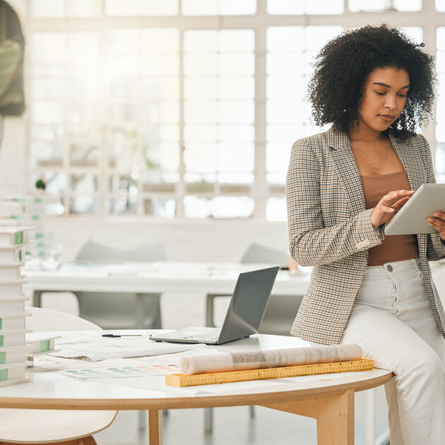 Vrouw zit op bureau en kijkt serieus naar haar ipad.
