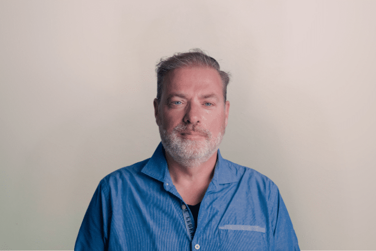 medewerker Qredits Wim van de Groep man in blauw shirt voor grijze achtergrond