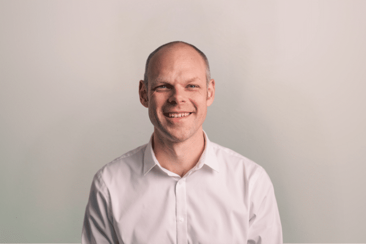 Elmer medewerker Qredits man in wit shirt voor grijze achtergrond