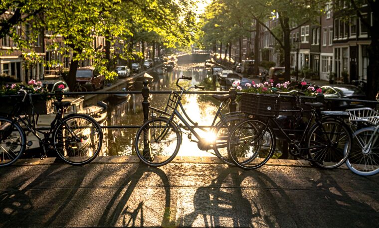 Afbeelding op de Amsterdamse grachten met fietsen tegen de reling. 