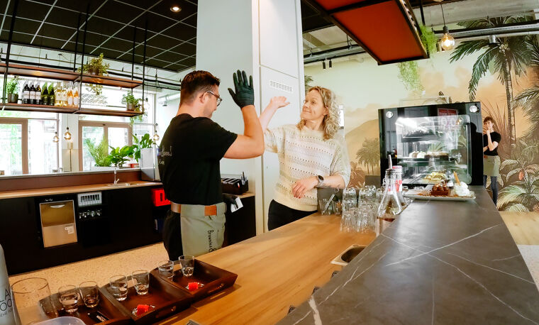 Een man en vrouw geven elkaar een high-five achter de bar.