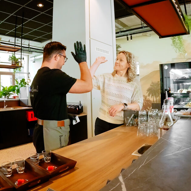 Een man en vrouw geven elkaar een high-five achter de bar.