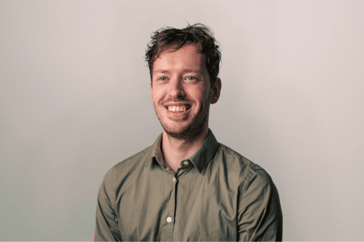 Floris medewerker Qredits man in groen shirt voor grijze achtergrond