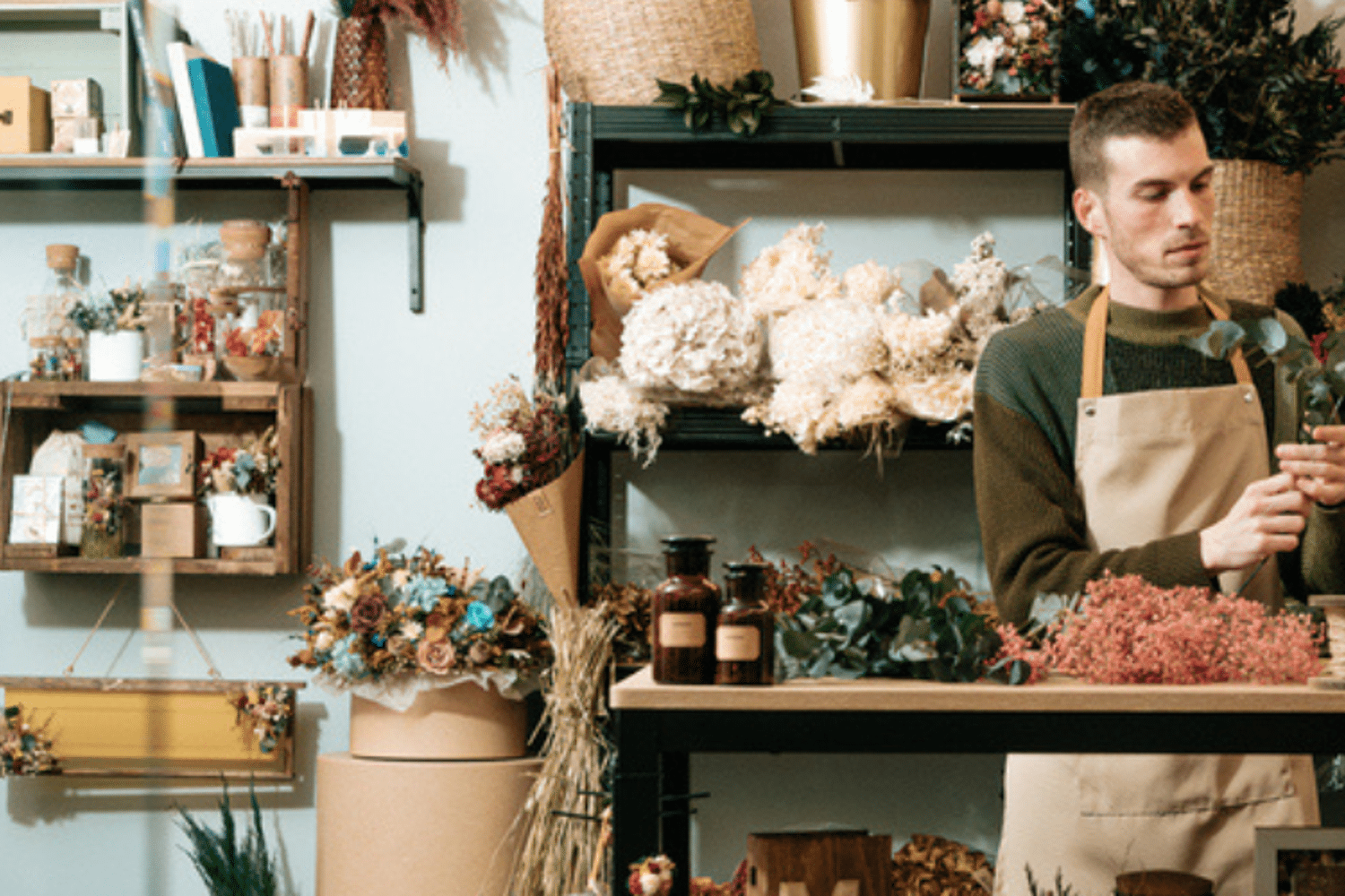 Header van een man in een bloemenwinkel die bloemen aan het schikken is.