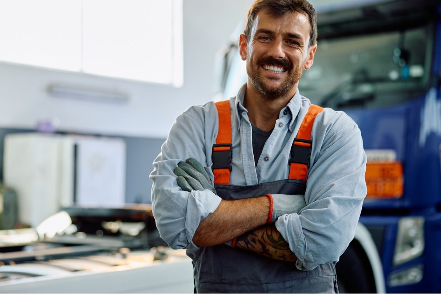 Lachende man met overal staat met handen over elkaar voor vrachtwagen.
