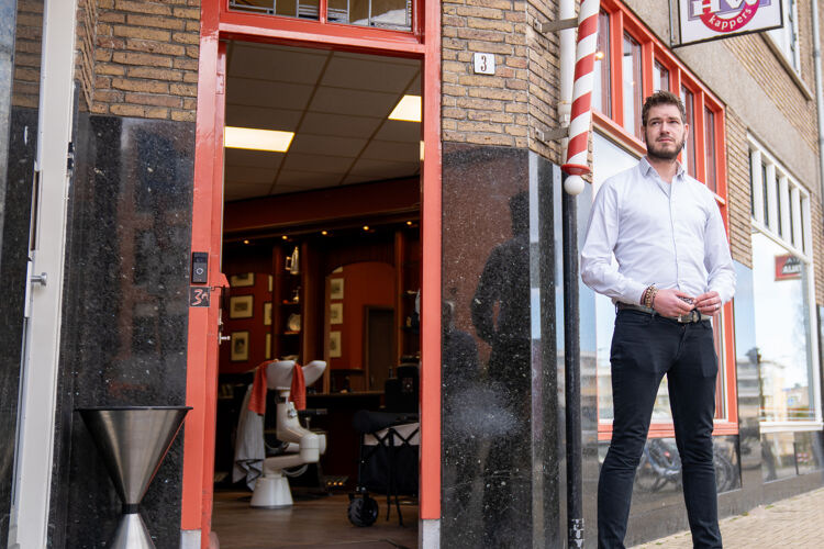 man-met-overhemd-staat-voor-kappers-zaak