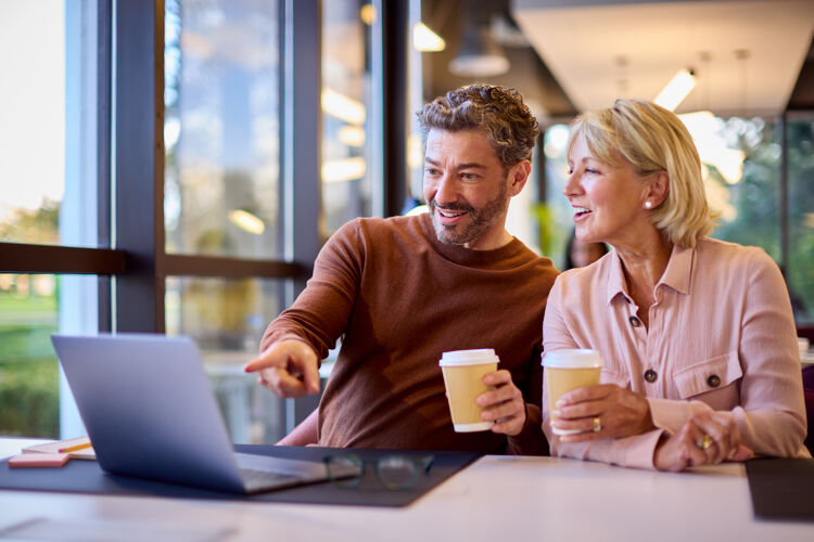 man-wijst-naar-laptop-naast-vrouw