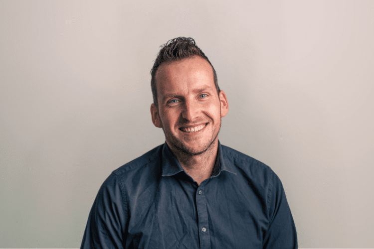 Dennis medewerker Qredits man in blauw shirt voor grijze achtergrond