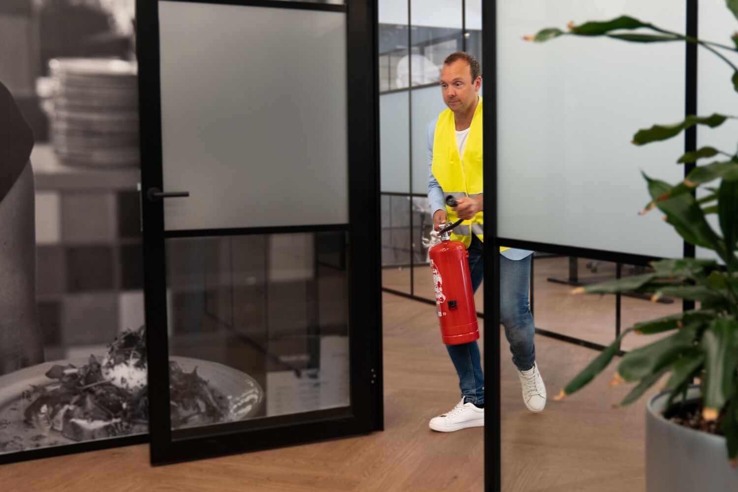 Man met geel hesje en brandblusser rent naar binnen. 