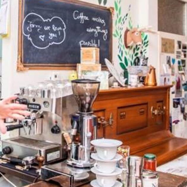 Vrouw staat in een koffiezaak en maakt koffie