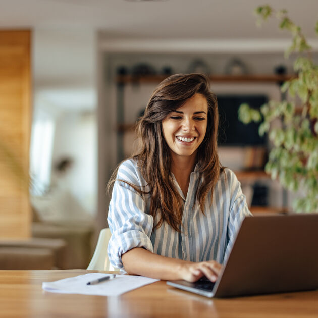 Vrouw kijk lachend naar laptop.