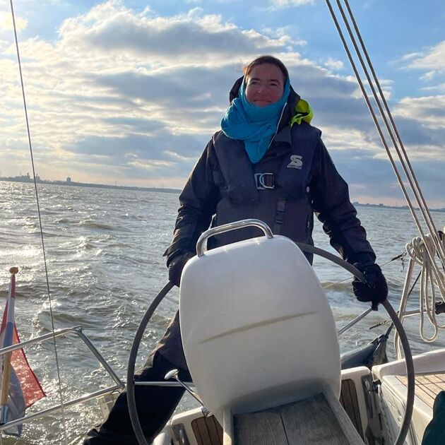 Qredits coach rolande wouda Staat achter het stuur op een boot in de zee met de Nederlands vlag