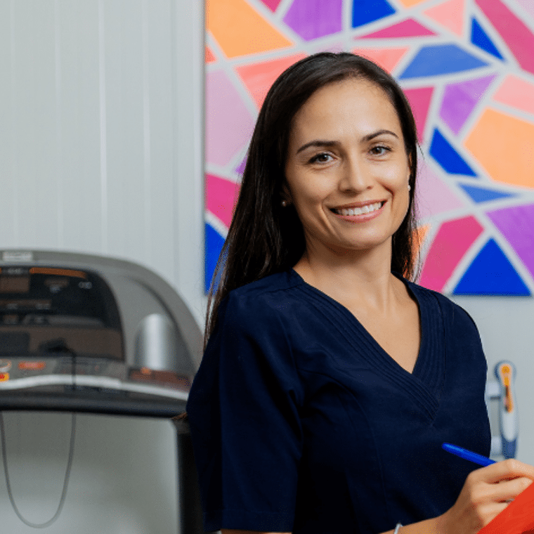 Vrouw in blauwe bloes schrijft in een mapje in een fysiotherapie praktijk
