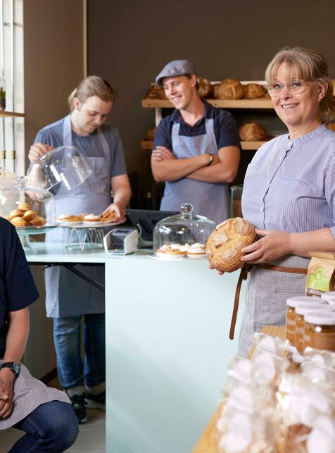 Een team staat in bakkerij en laat vers brood zien