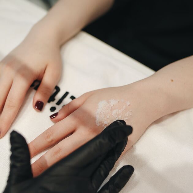 Vrouw in beauty salon met gelakte nagels krijgt zalf op haar hand.