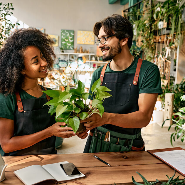 Man en vrouw staan met een plant bij een balie en kijken naar elkaar. 