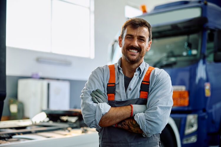 man-met-overall-staat-lachend-voor-vrachtwagen