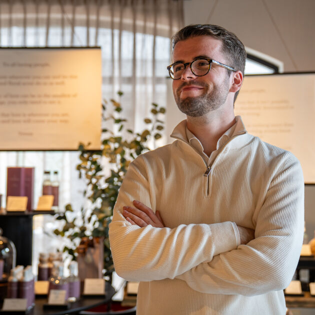 Man met bril staat met handen over elkaar in winkel.