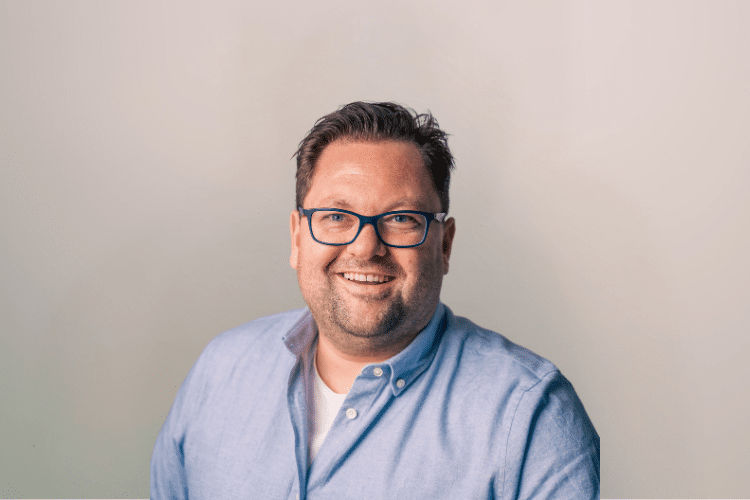 Marnix medewerker Qredits man in blauw shirt voor grijze achtergrond