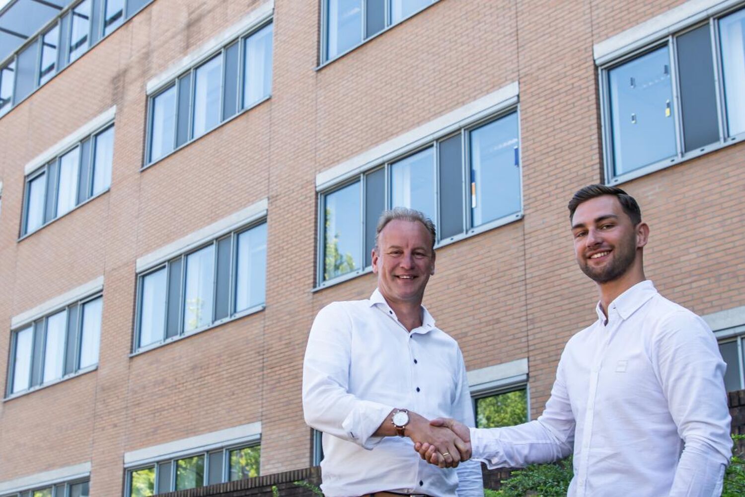 Qredits en Campus Offices slaan handen in één twee mannen schudden de hand buiten voor een gebouw