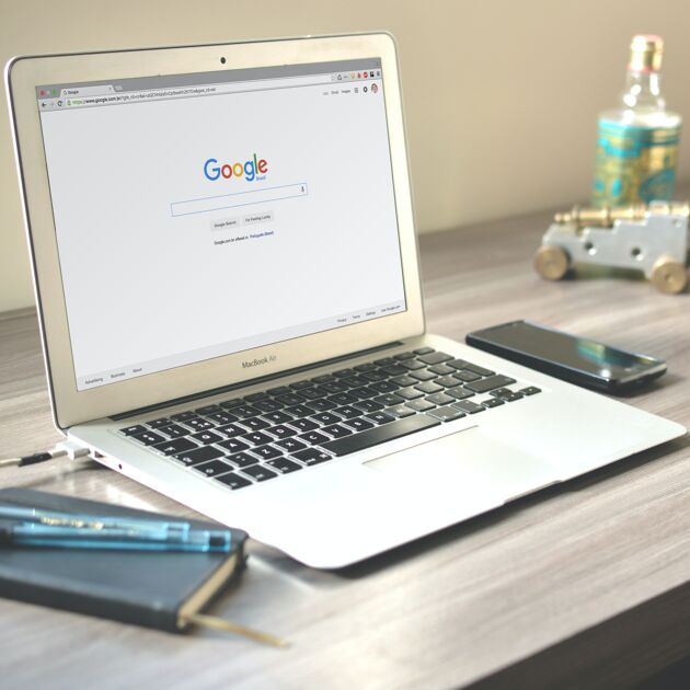 Een laptop waar Google op is gezocht met een schrift en telefoon 