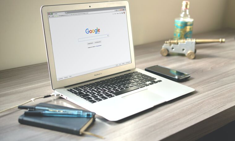 Een laptop waar Google op is gezocht met een schrift en telefoon 