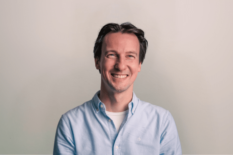 Stefan medewerker Qredits man in blauw shirt voor grijze achtergrond
