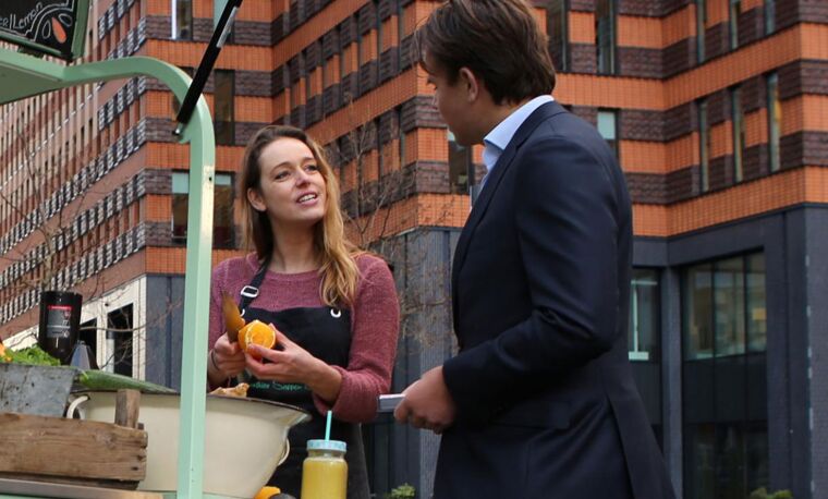 Vrouw in schort maakt drinken klaar voor man in pak buiten
