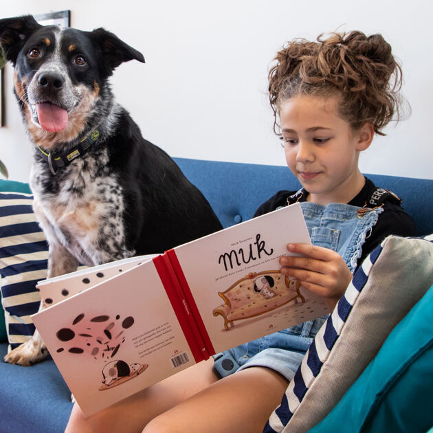 Meisje leest boek en er zit een hond naast
