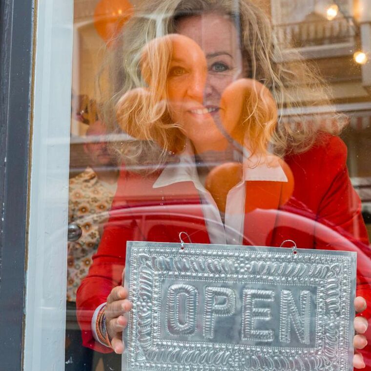 Vrouw kijkt door het raam van haar zaak