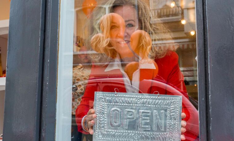 Vrouw kijkt door het raam van haar zaak