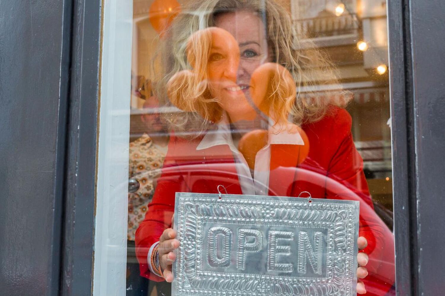 Vrouw kijkt door het raam van haar zaak
