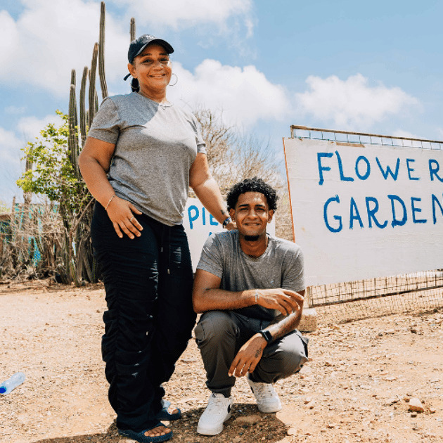 Man en vrouw poseren voor een bord met flowergarden