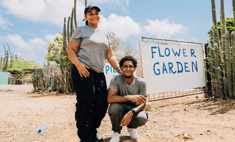 Man en vrouw poseren voor een bord met flowergarden