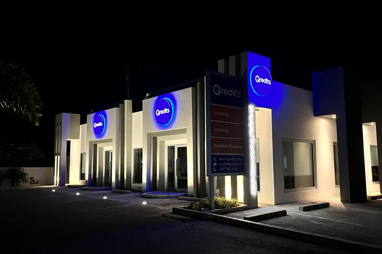 Wit gebouw op Aruba in de nacht met lichtgevende logos 