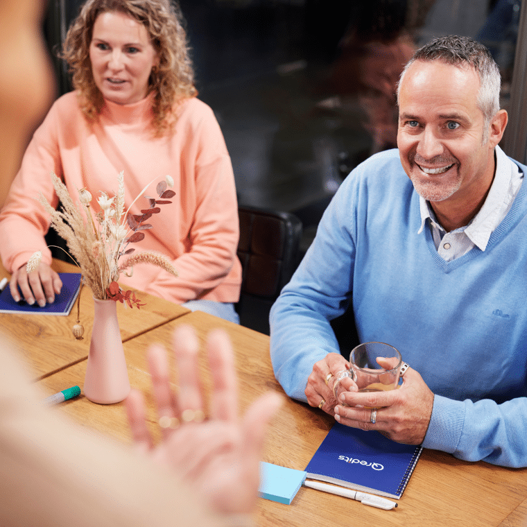 tijdens een zakelijke training lacht een man naar de qredits trainer