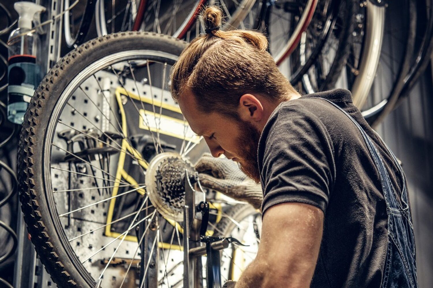 Een man met een overall aan sleutelt aan een fiets.